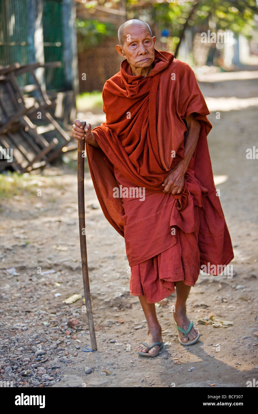Myanmar Birmania, Stato di Rakhine, Sittwe. Un vecchio monaco buddista a piedi giù per una strada di Sittwe. Foto Stock