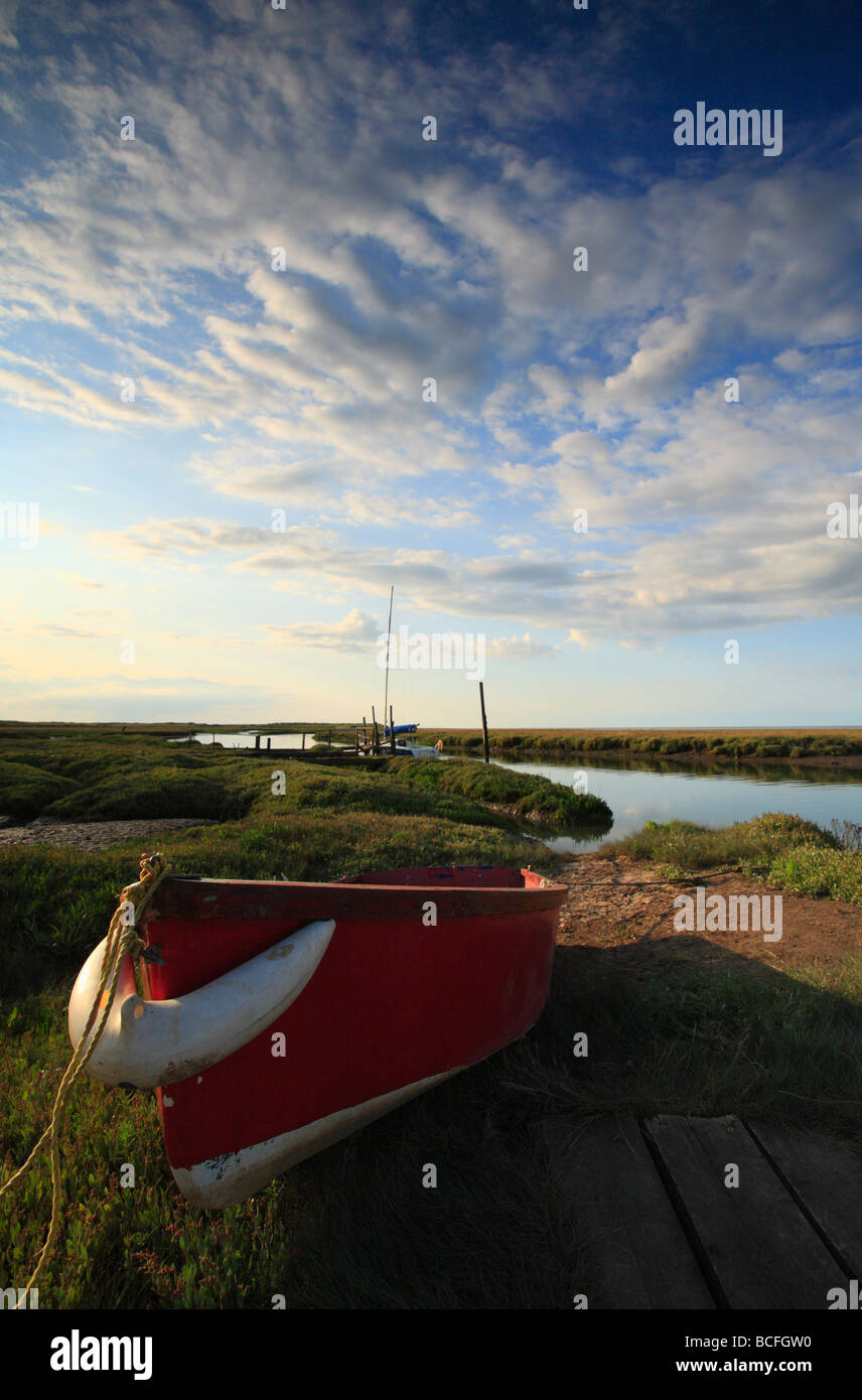 Un rosso barca a remi in appoggio sul marsh a Thornham sulla Costa North Norfolk. Foto Stock