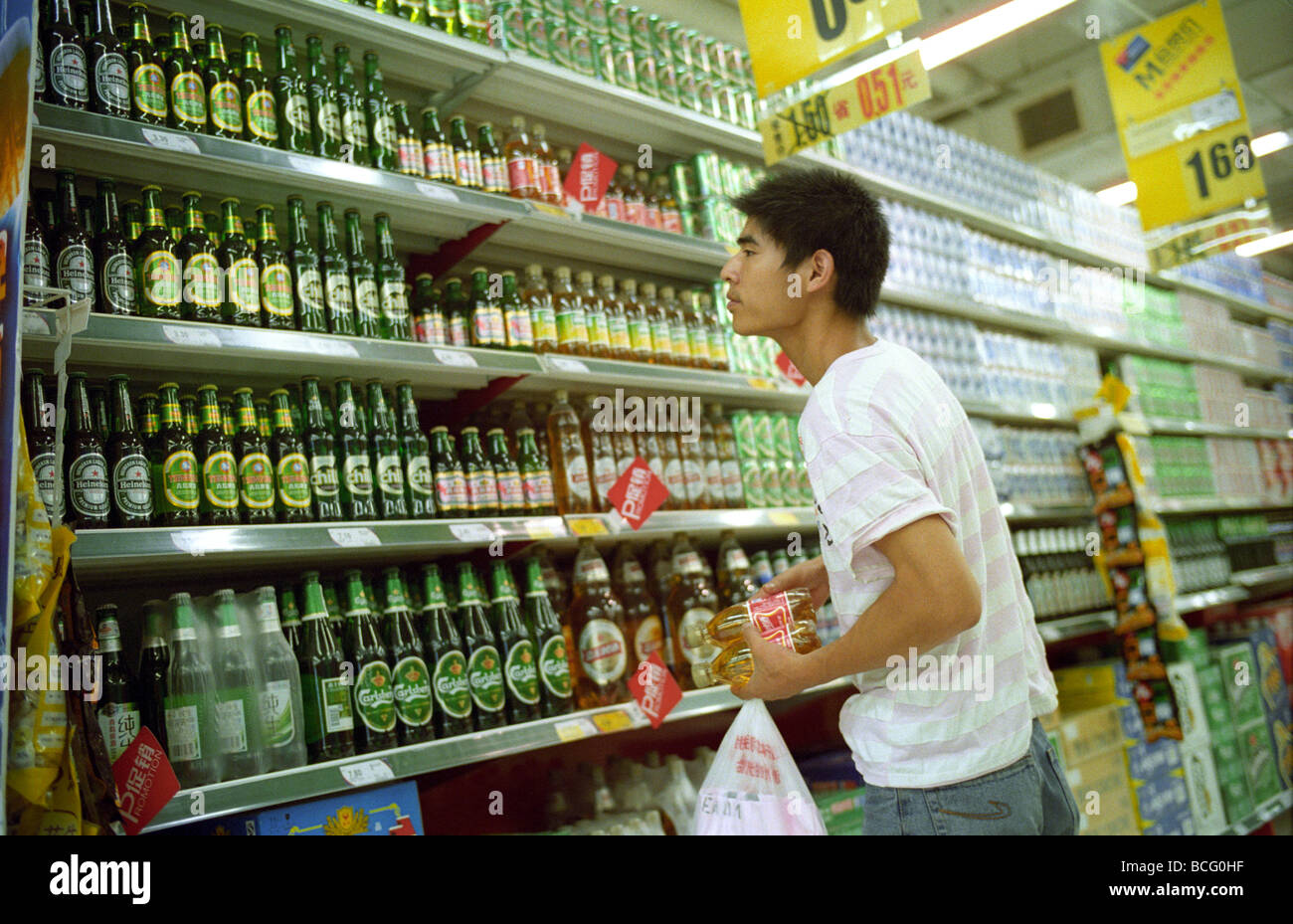Uomo cinese shopping presso il contatore di birra al supermercato Tesco a Pechino in Cina. 2009 Foto Stock