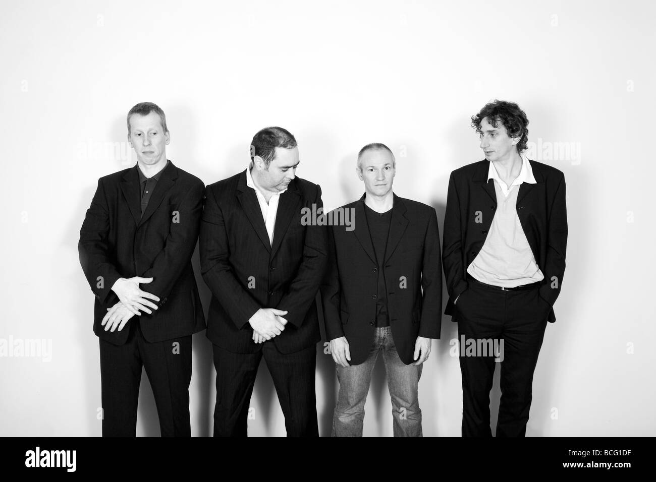 Quattro uomini line up contro una parete Foto Stock