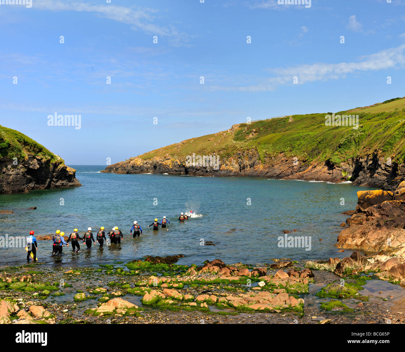 PORT QUIN, CORNWALL, Regno Unito - 13 GIUGNO 2009: Gruppo di persone Coastering in The Cove Foto Stock