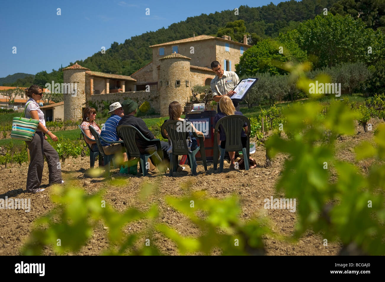 Un gruppo seduto ascoltando un parlare di vinificazione in un vigneto attorno a vini Gigondas denominazione Francia Foto Stock