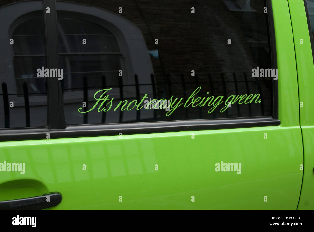 La scrittura sulla finestra di una piccola automobile verde dicendo che non è facile essere verde Foto Stock