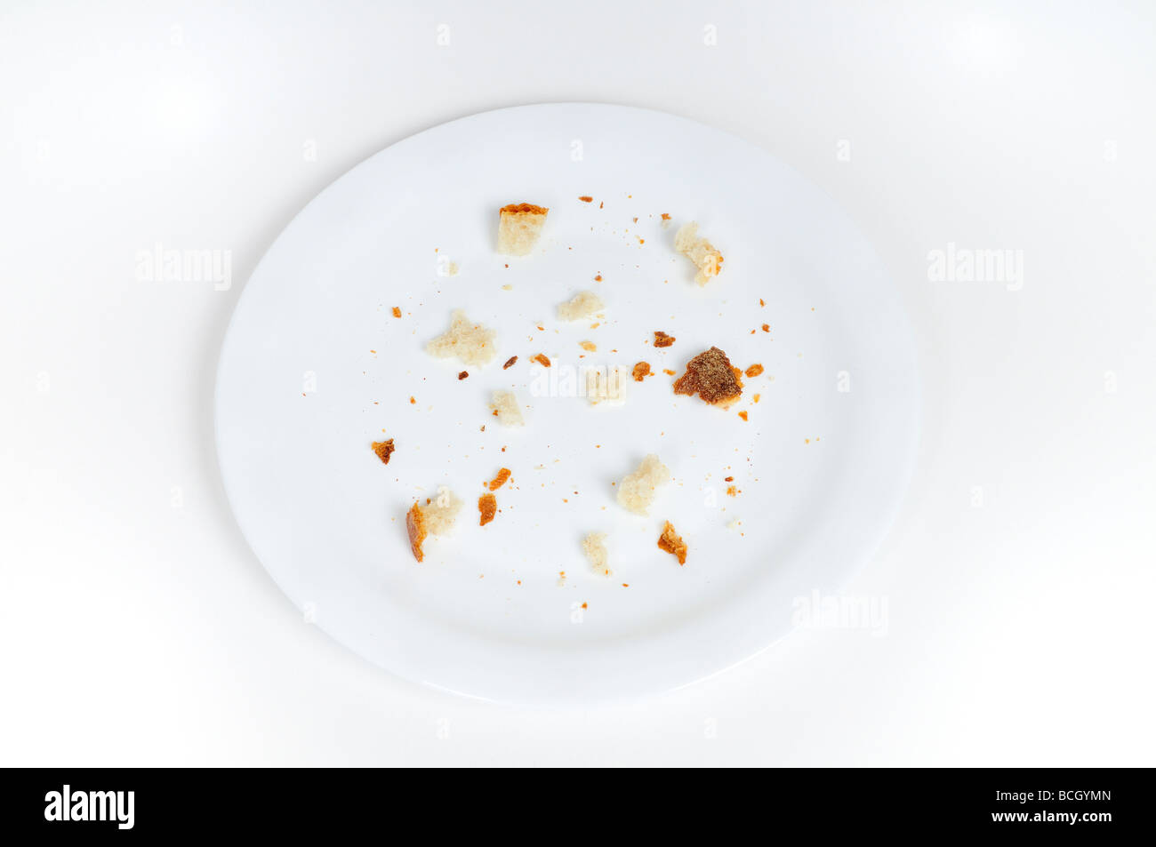 Briciole di pane sulla piastra, sfondo bianco Foto Stock