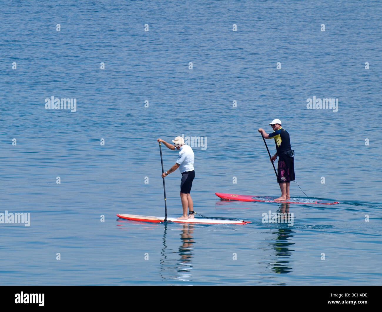 Stand up paddleboarding su un mare piatto Foto Stock