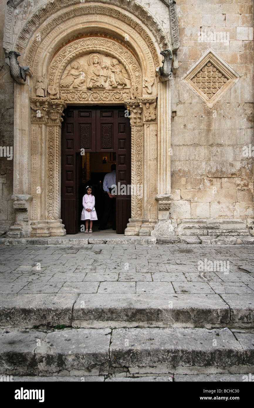 Monte Sant' Angelo Puglia Italia una giovane ragazza sta nel vano della porta del XII C chiesa di Santa Maria Maggiore durante la massa Foto Stock