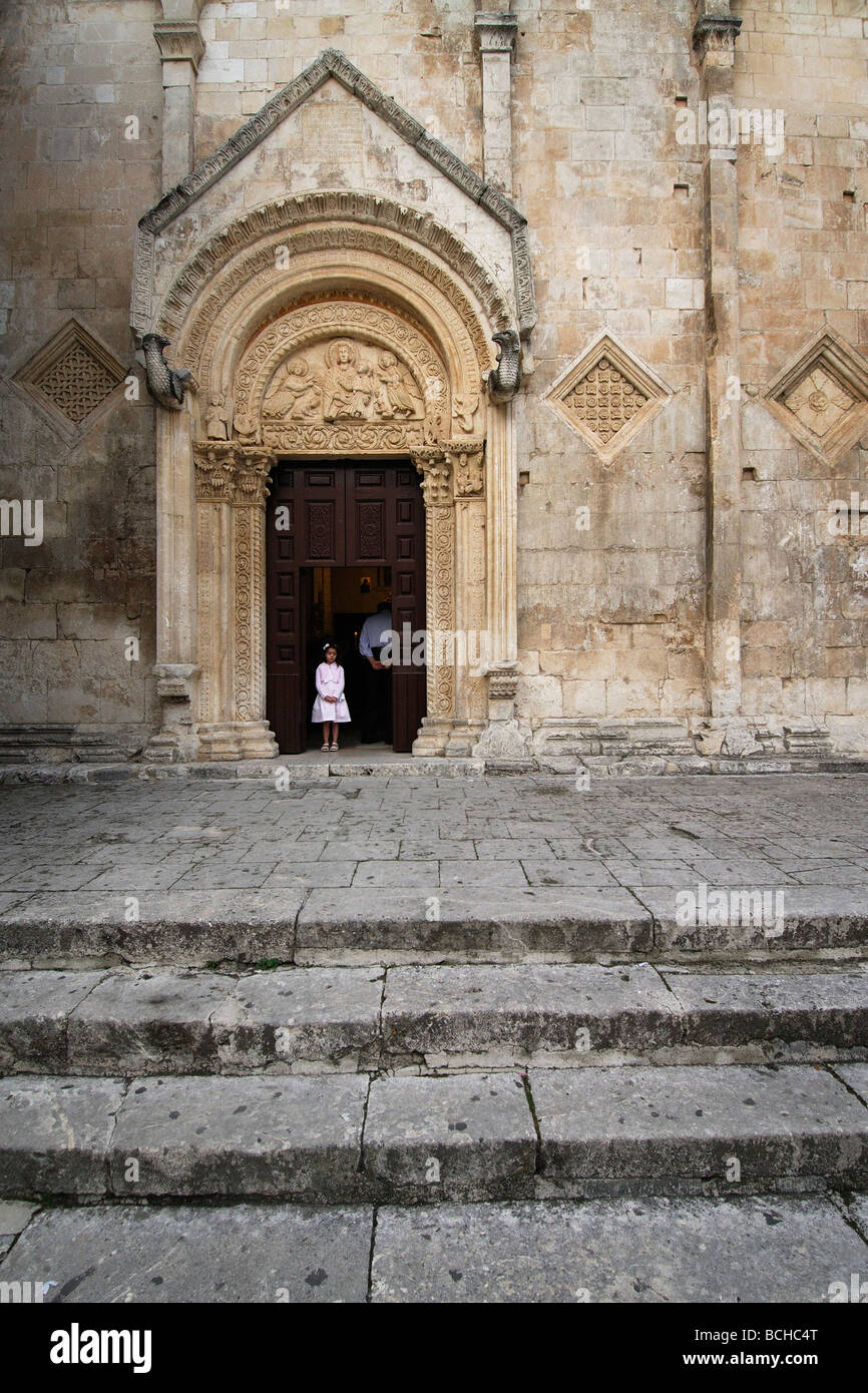 Monte Sant' Angelo Puglia Italia una giovane ragazza sta nel vano della porta del XII C chiesa di Santa Maria Maggiore durante la massa Foto Stock