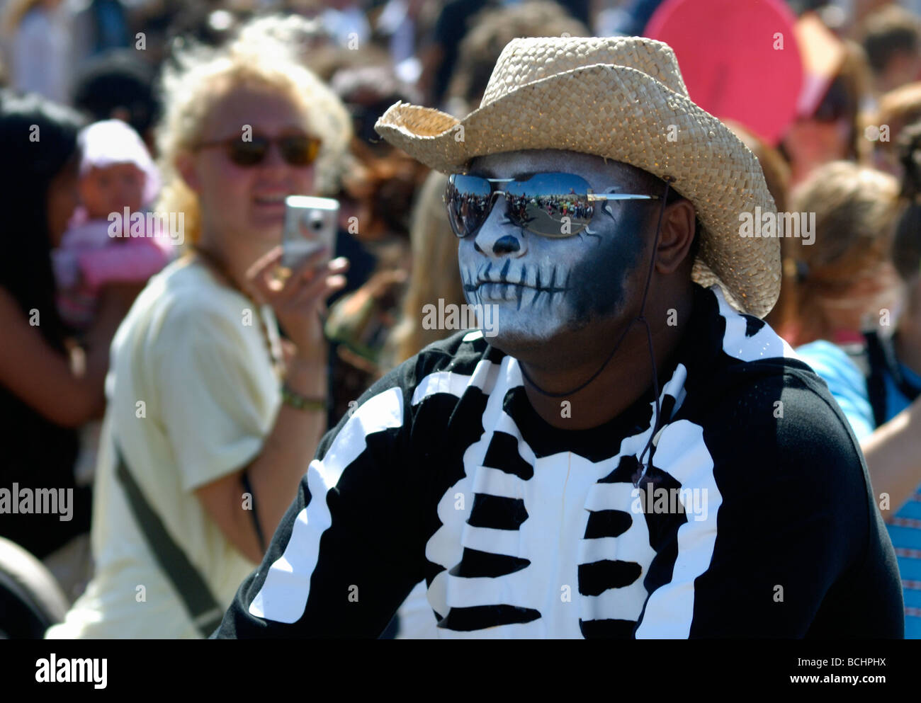 Uomo nero vestito come scheletro con occhiali da sole e cappello di paglia in street parade Foto Stock