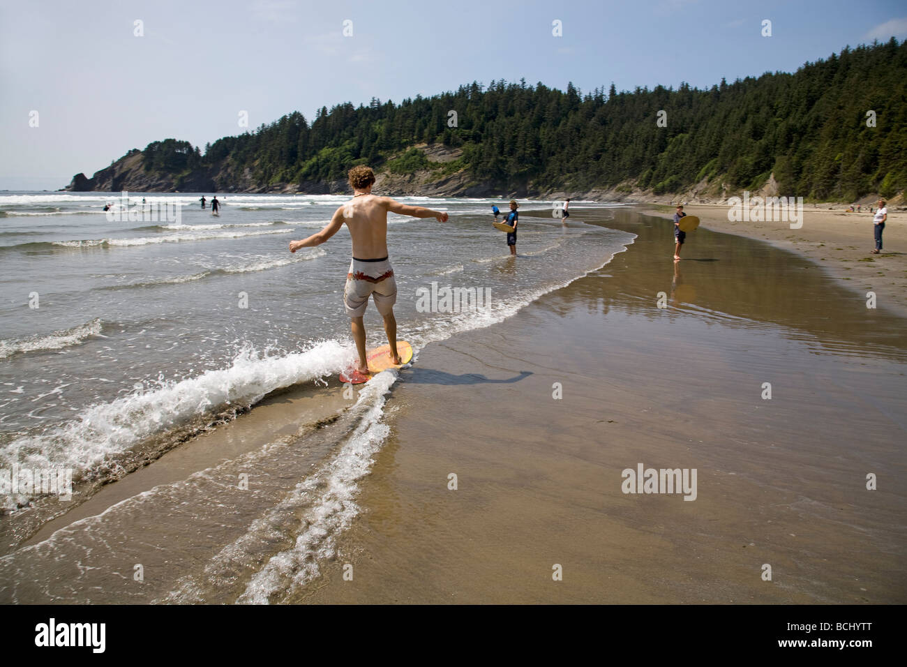 Un adolescente su una skim board nel surf a Oswald West State Park su Oregon costa del Pacifico Foto Stock