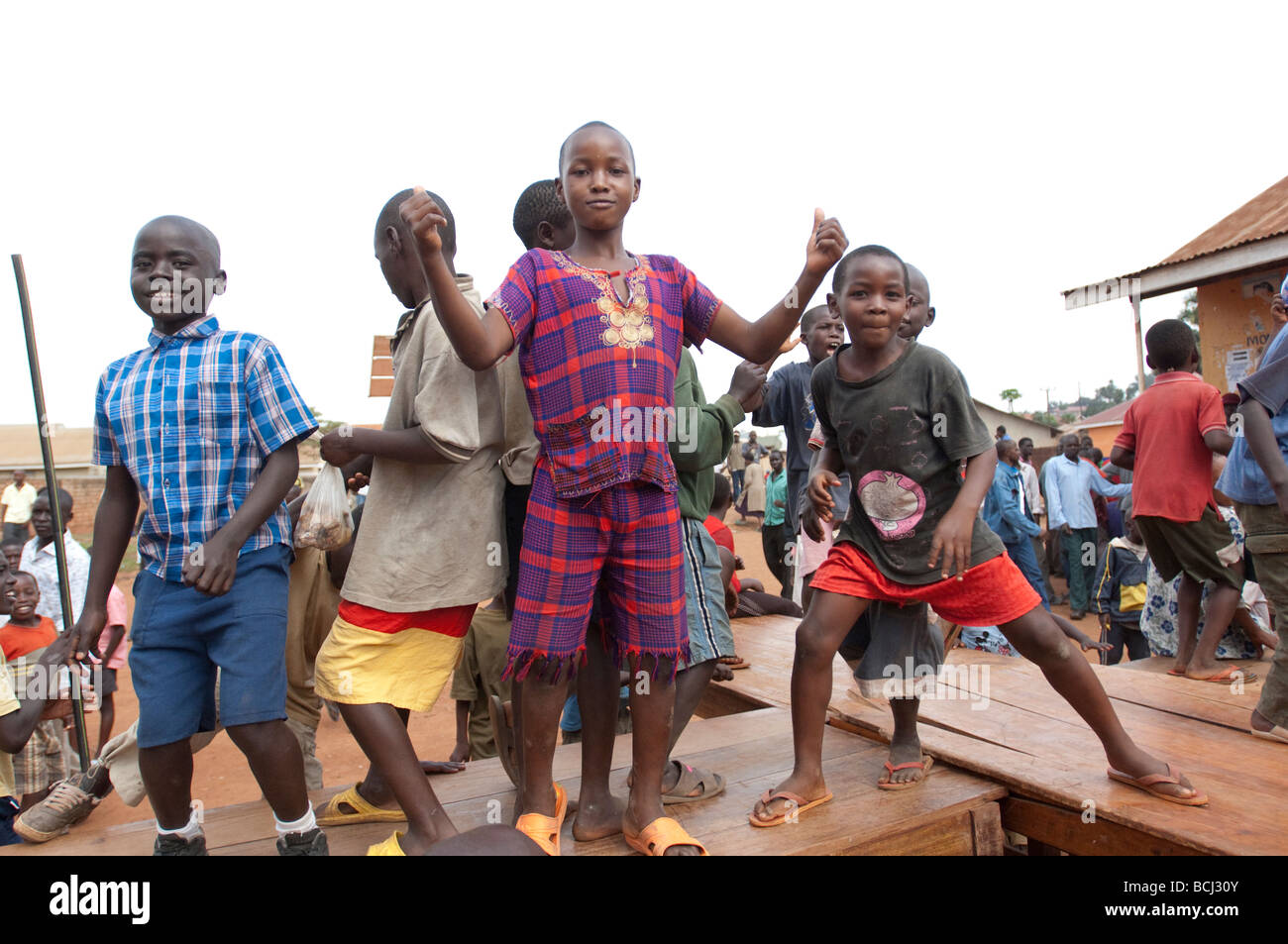 I bambini danza sulla scrivania al di fuori della scuola nella baraccopoli di Kampala Foto Stock