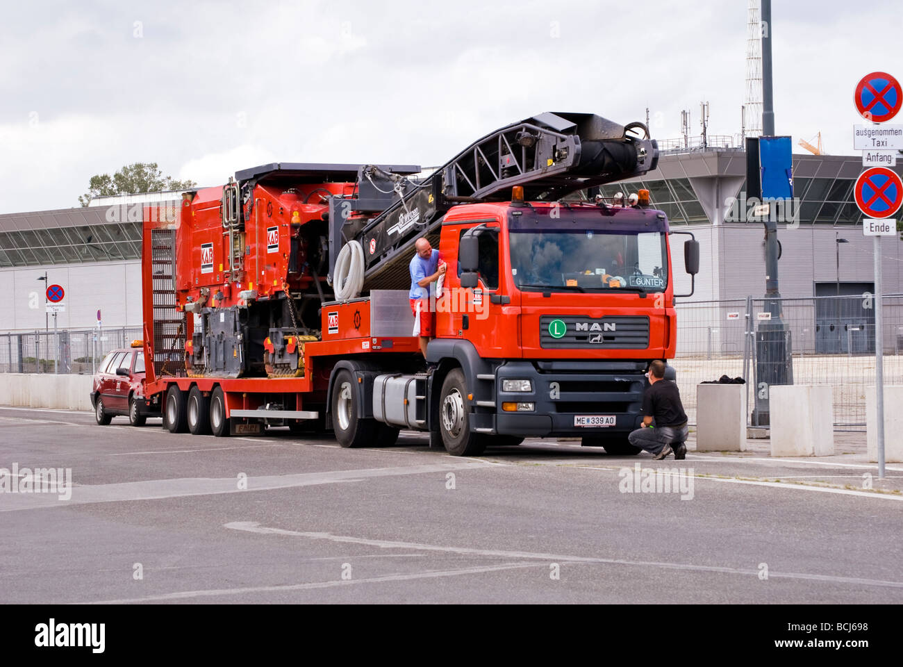 Uomo rosso carrello essendo pulito da due conducenti che trasportano carichi pesanti, Vienna, Austria Foto Stock