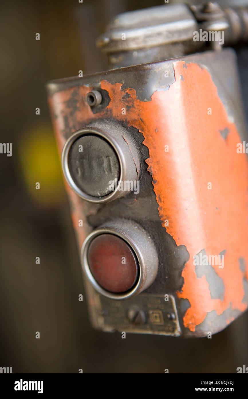 Dettaglio della macchina in fabbrica dei controlli con i pulsanti per avviare e interrompere la casella di controllo ha scaglie di vernice arancione Foto Stock