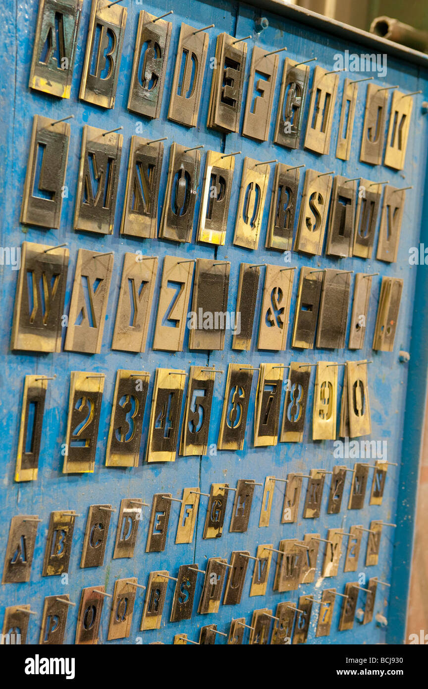 Lettera di metallo stencil appeso alla parete blu in rack factory Foto Stock