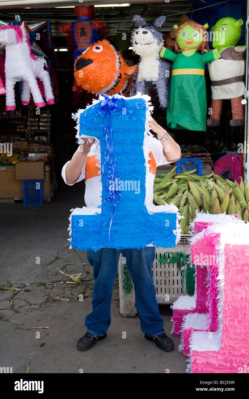 Persona presso shop azienda piñata per la forma del numero 1 di oscurare il suo volto Foto Stock