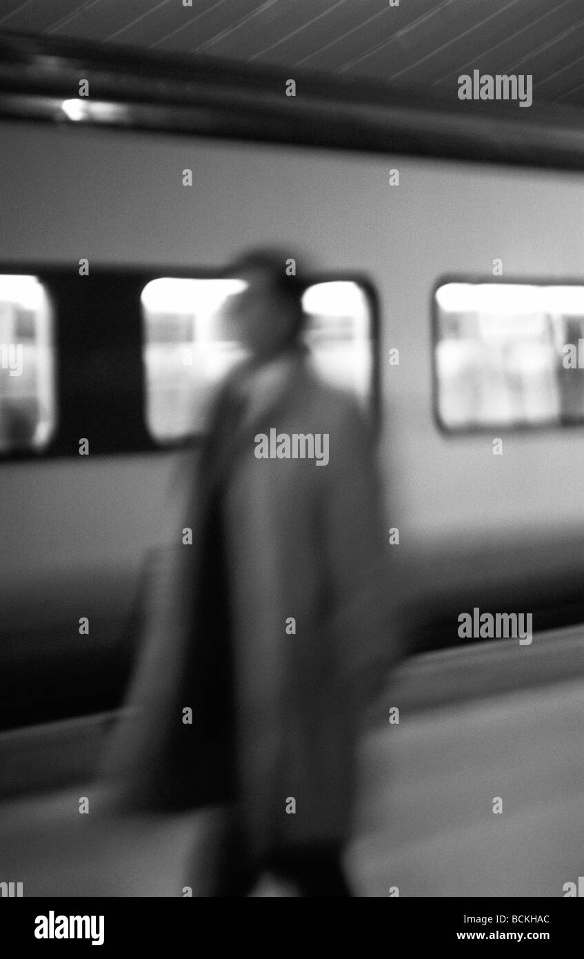 Uomo in piedi sulla piattaforma di fronte alla metropolitana treno, b&W Foto Stock