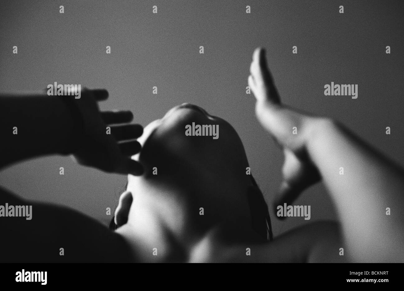 Bambino con la testa indietro alzando le mani verso il viso, a basso angolo di visione, b&W Foto Stock