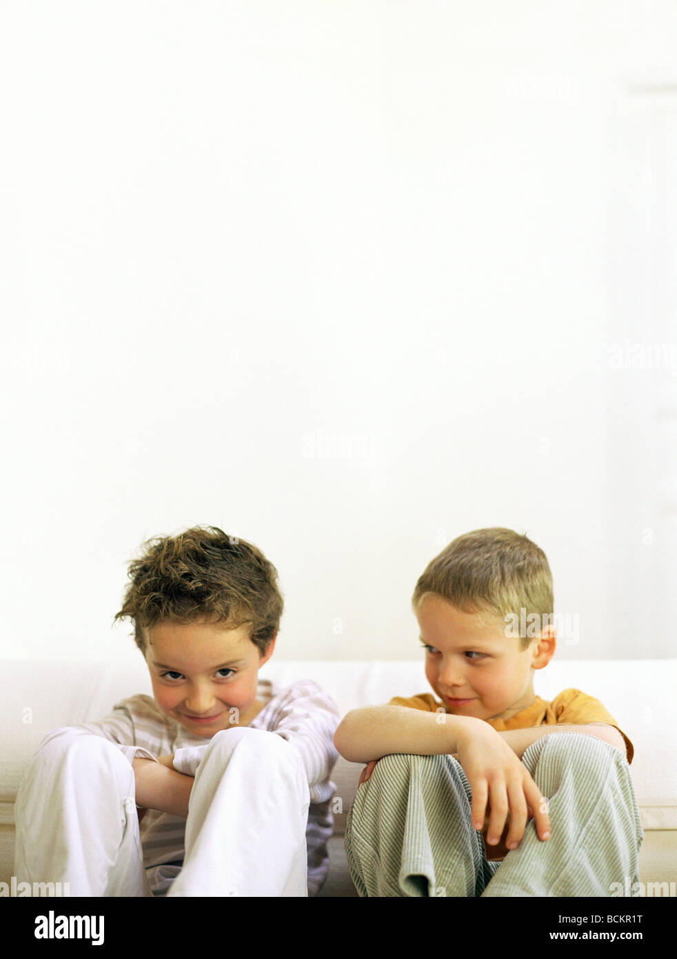 Due ragazzi seduti fianco a fianco Foto Stock