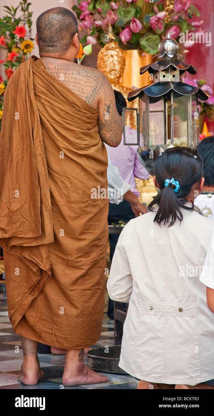 Thailandia. Un ben tatuati monaco buddista prega al Phra Pathom Chedi che ha il più grande stupa in Thailandia. Foto Stock