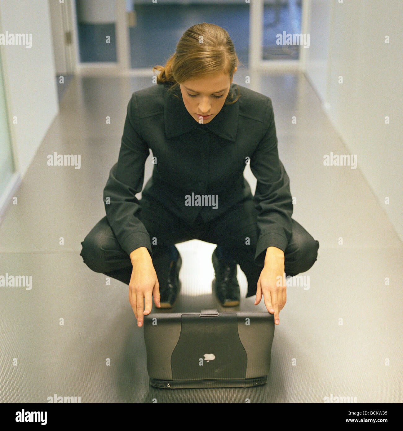 Donna accovacciato nella parte anteriore del computer portatile Foto Stock