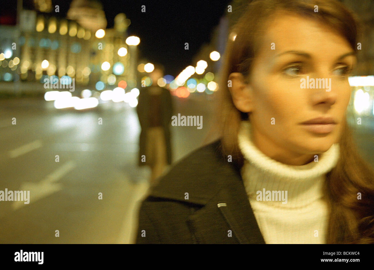 Giovane donna a piedi in strada di notte Foto Stock