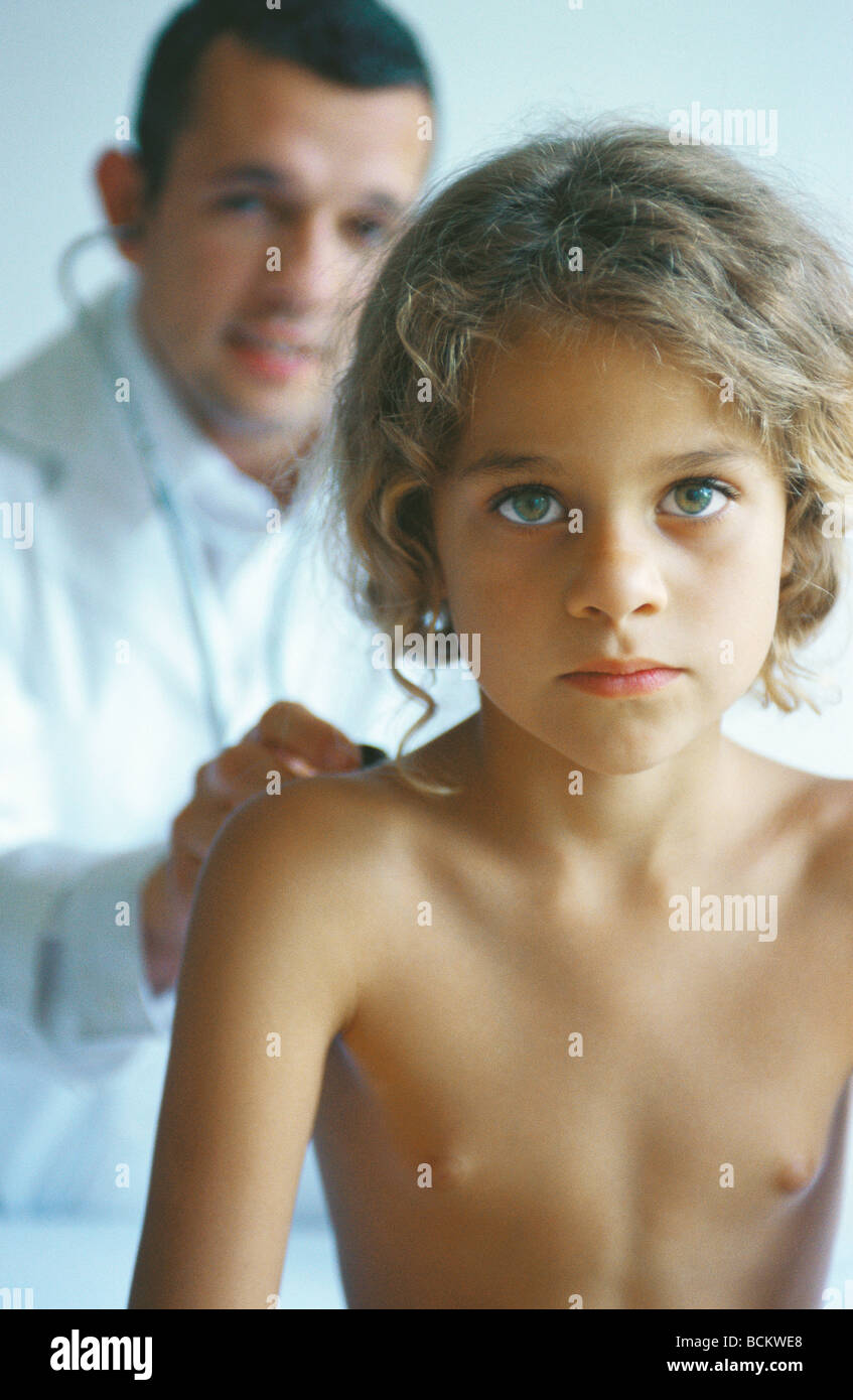 Medico esaminando bare chested bambino con uno stetoscopio Foto Stock