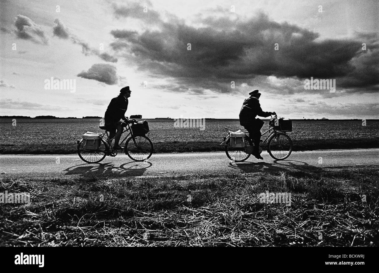 Due persone in bicicletta su strada attraverso campi, b&W Foto Stock