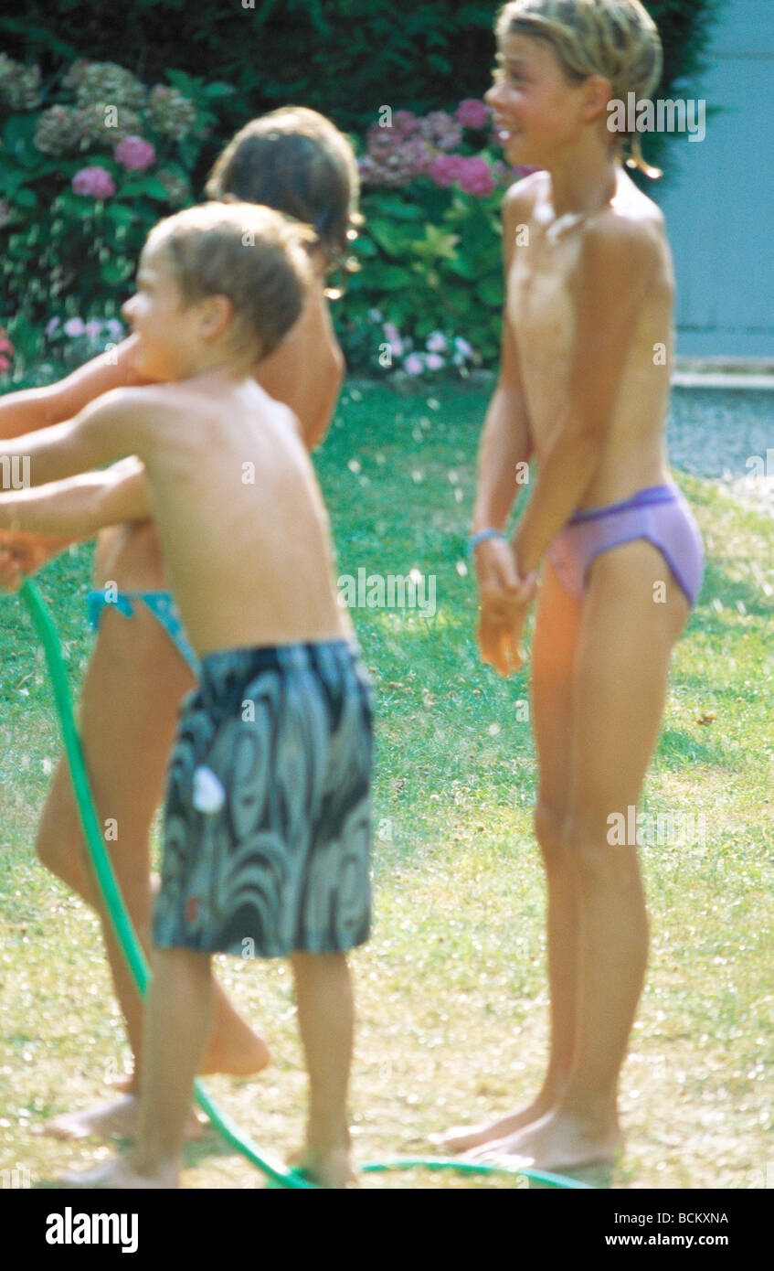 I bambini in piedi fuori in costumi da bagno con tubo flessibile Foto Stock