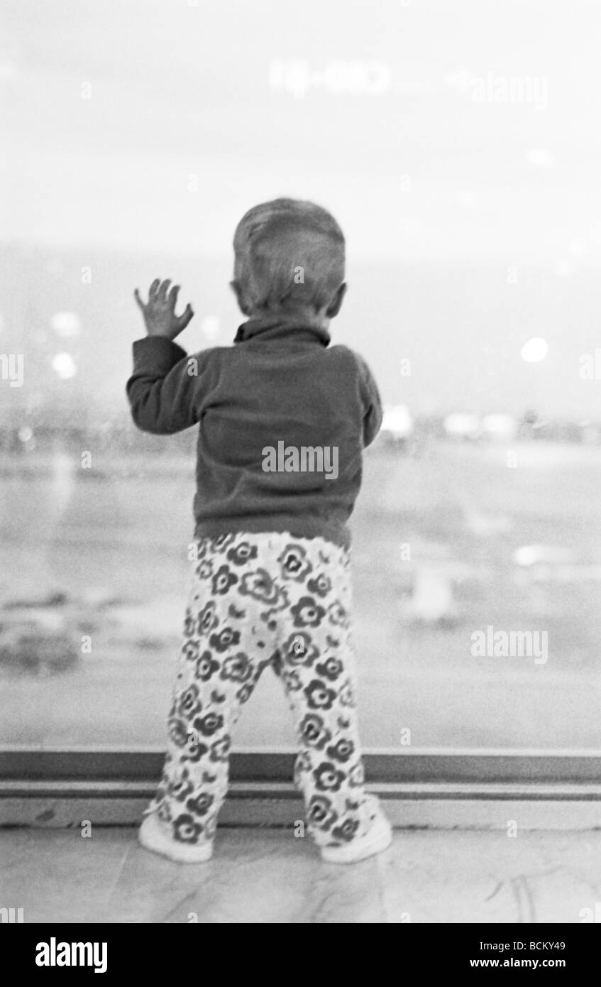 Bambino in piedi appoggiata contro il vetro della finestra, vista posteriore Foto Stock