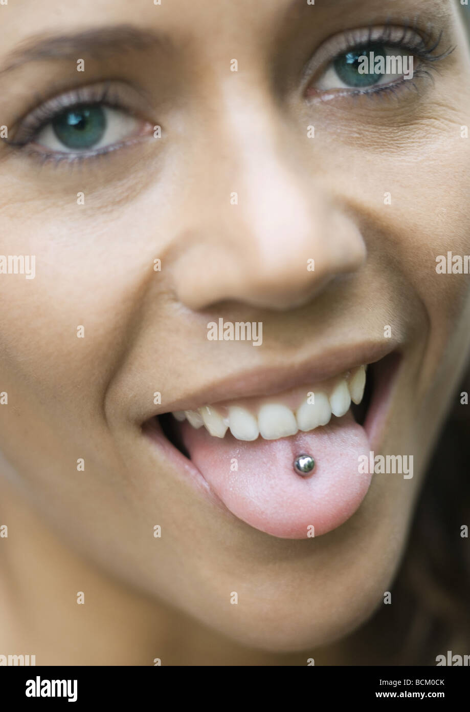 Donna spuntavano lingua, mostrando piercing, guardando la telecamera, close-up Foto Stock