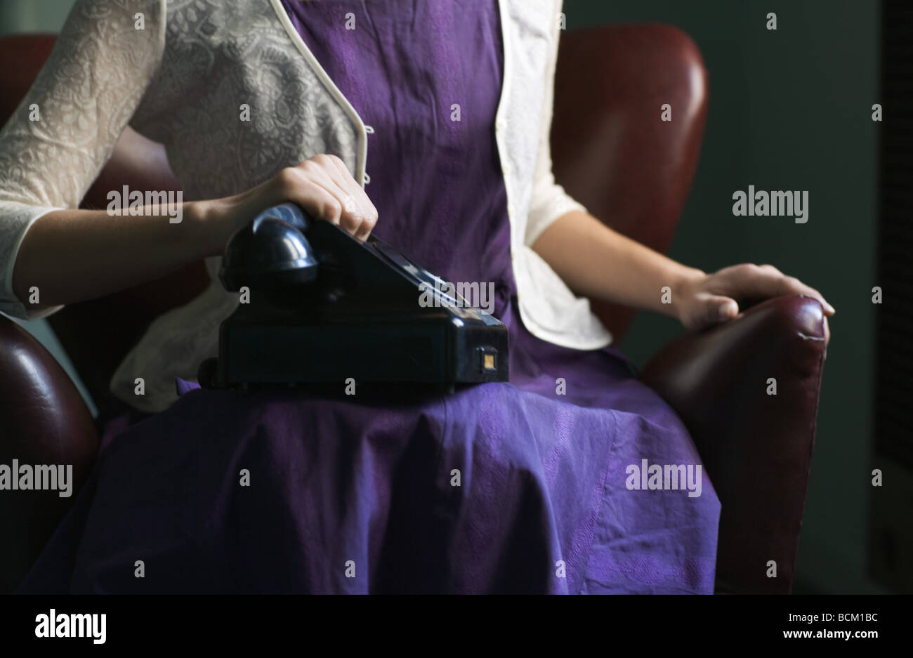 Donna abito in udienza con il telefono sul giro, mano sul ricevitore, vista ritagliata della sezione centrale Foto Stock
