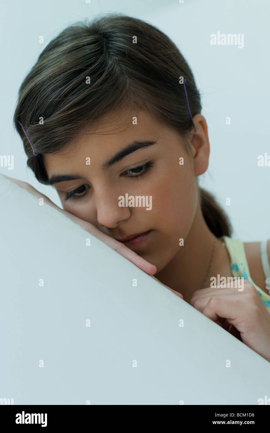 Teen ragazza appoggiata sul bordo della parete, guardando verso il basso, close-up Foto Stock