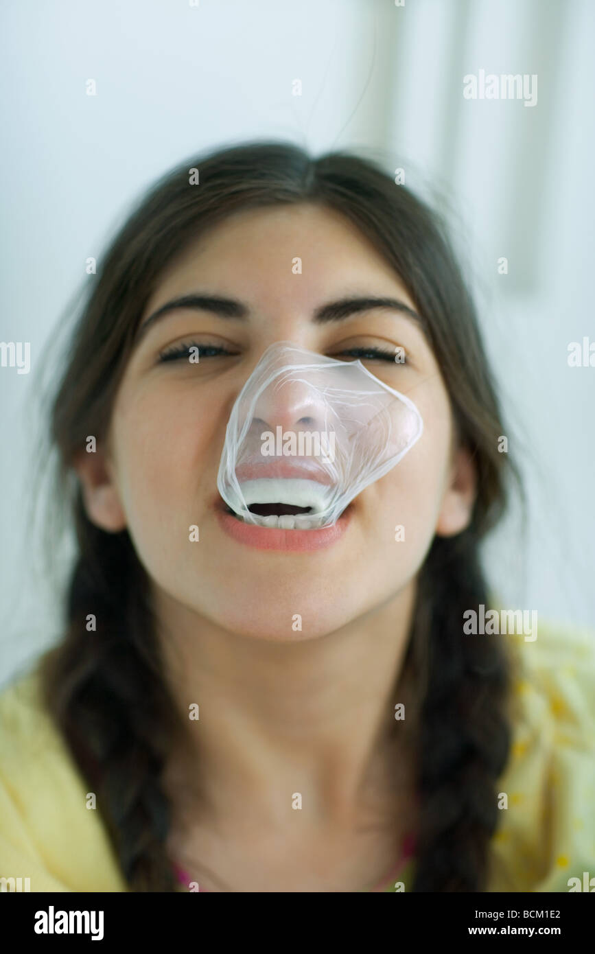 Close-up di giovane donna ridere con popped bubble gum bubble incollata alla faccia, headshot Foto Stock