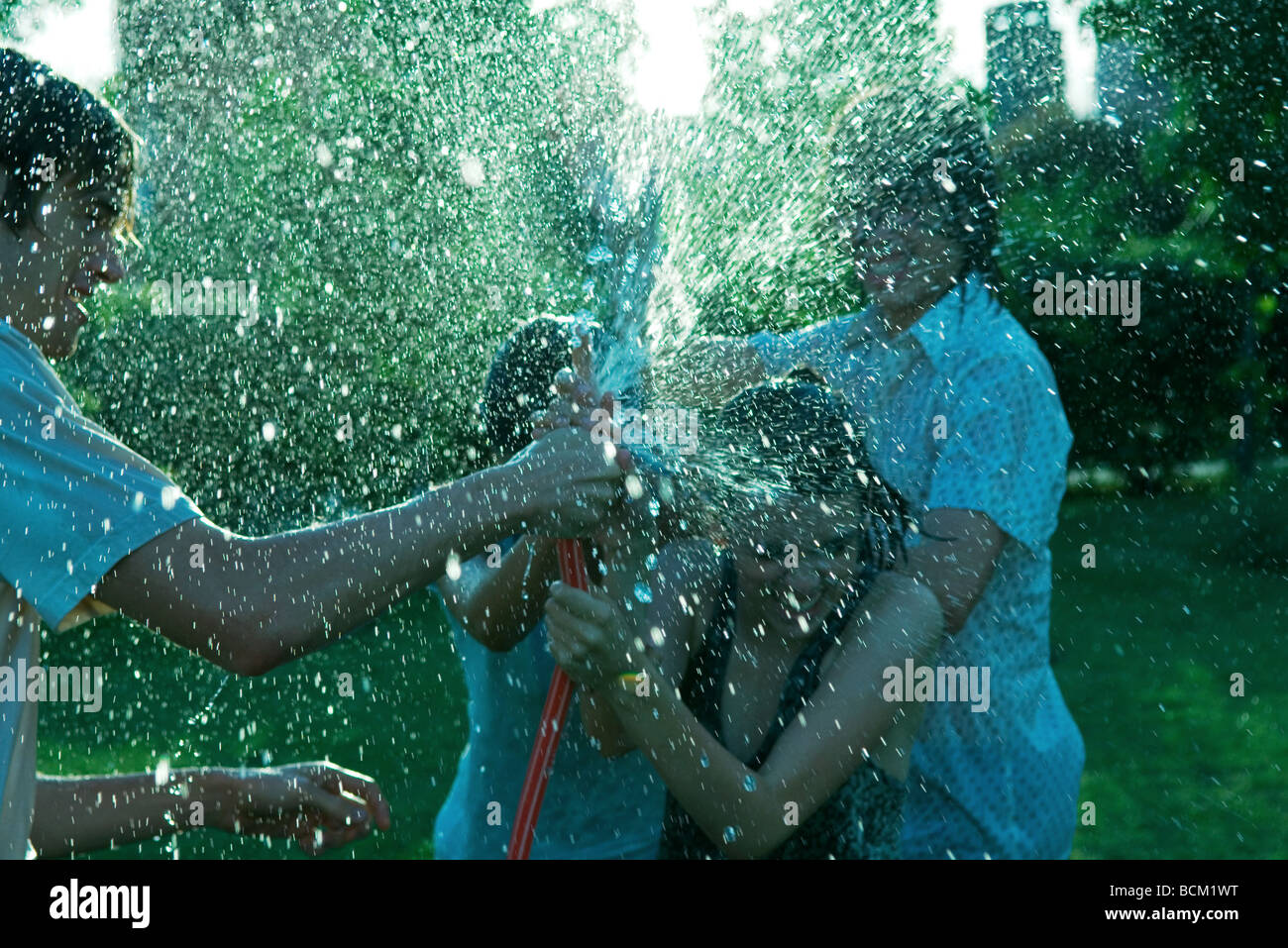 Giovani amici avente acqua lotta con tubo flessibile da giardino Foto Stock