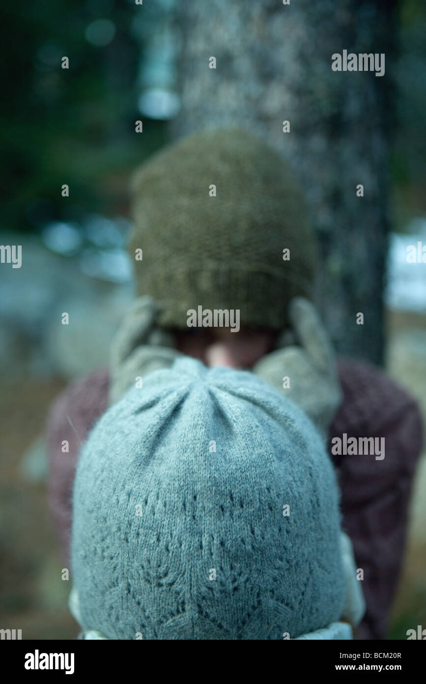 Due amici in piedi faccia a faccia, sia indossando cappelli invernali, volti oscurati Foto Stock