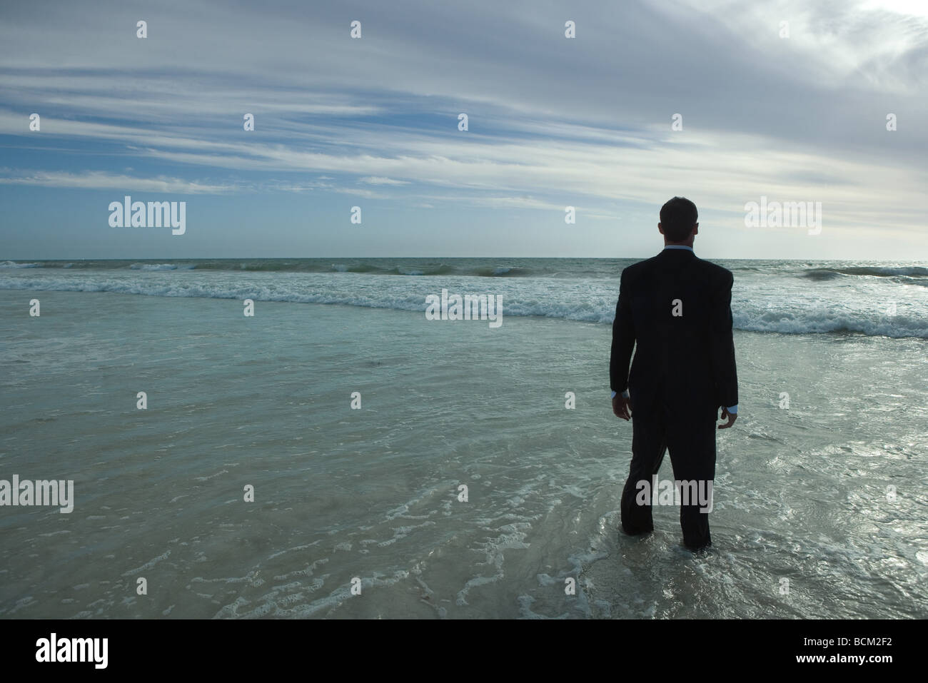 Imprenditore in piedi in mare, fissando orizzonte Foto Stock