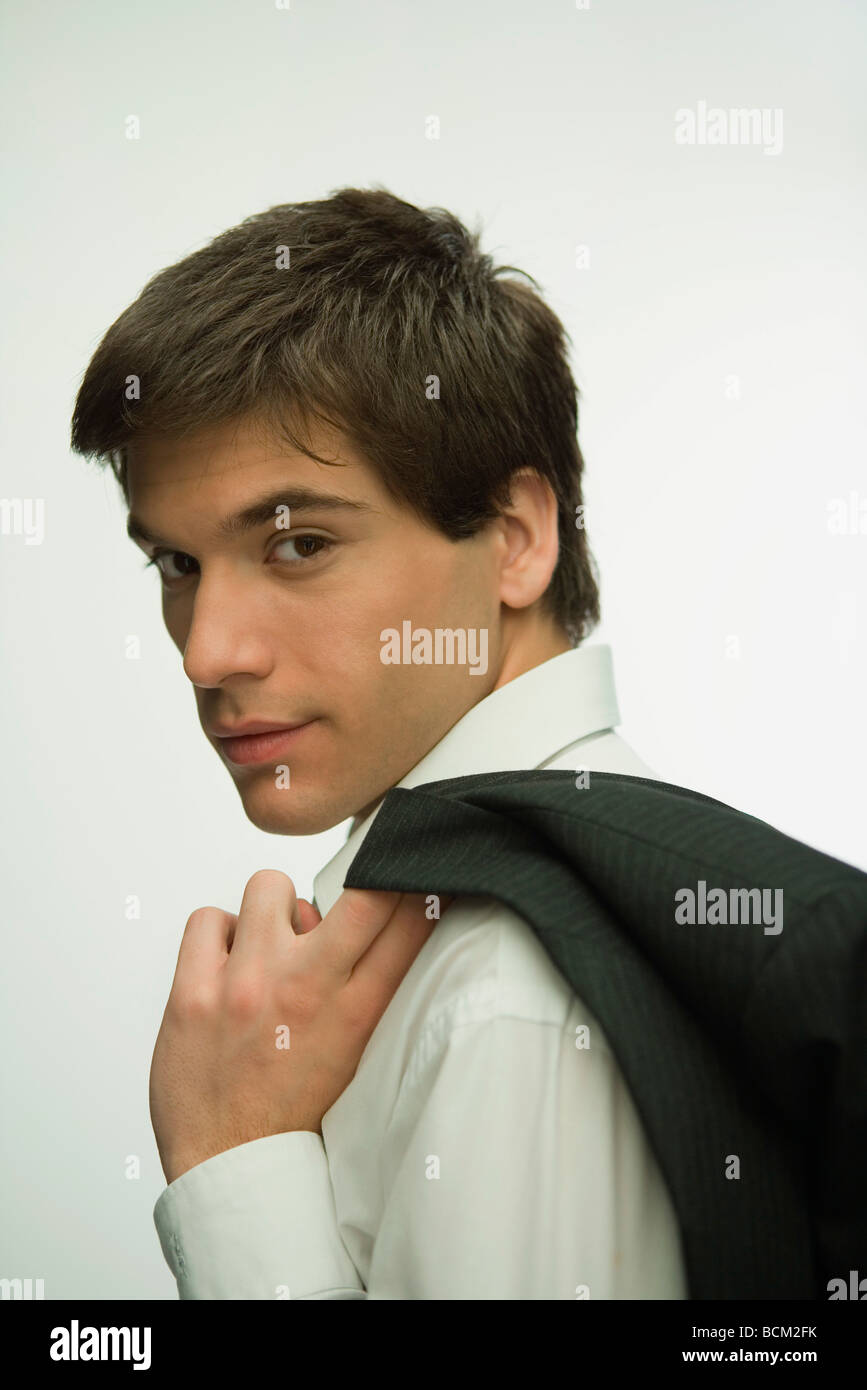 Giovane uomo camicia di contenimento, guardando sopra la spalla in telecamera Foto Stock