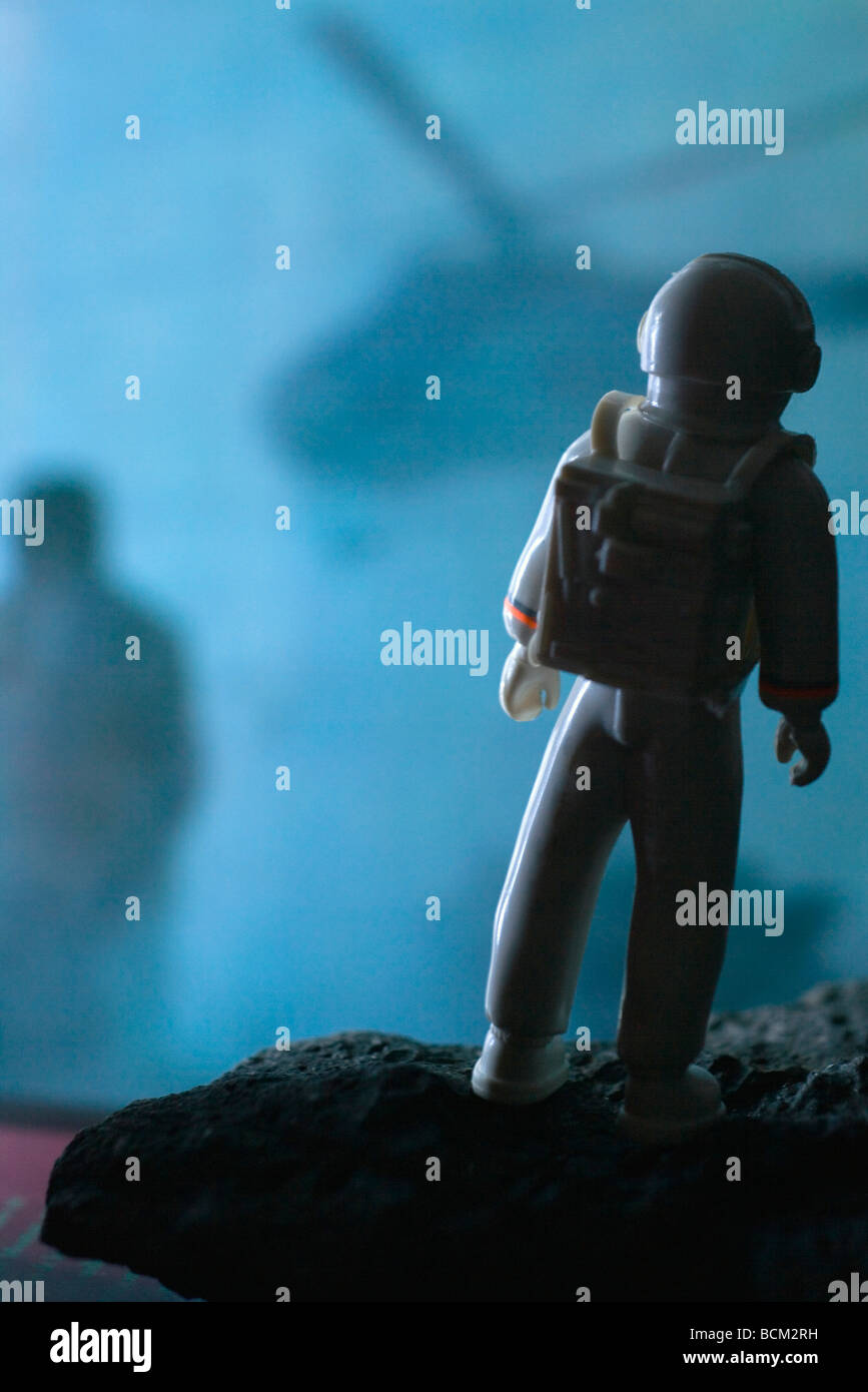 Astronauta in plastica guardando figura oscura in background Foto Stock
