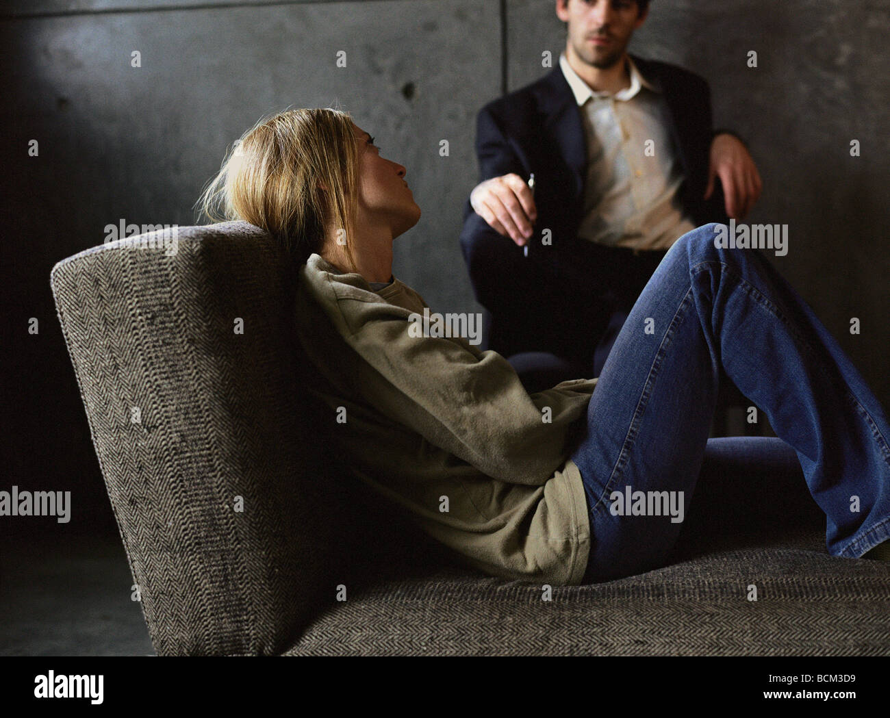 Giovane donna sdraiata su lettino guardando psicologo Foto Stock