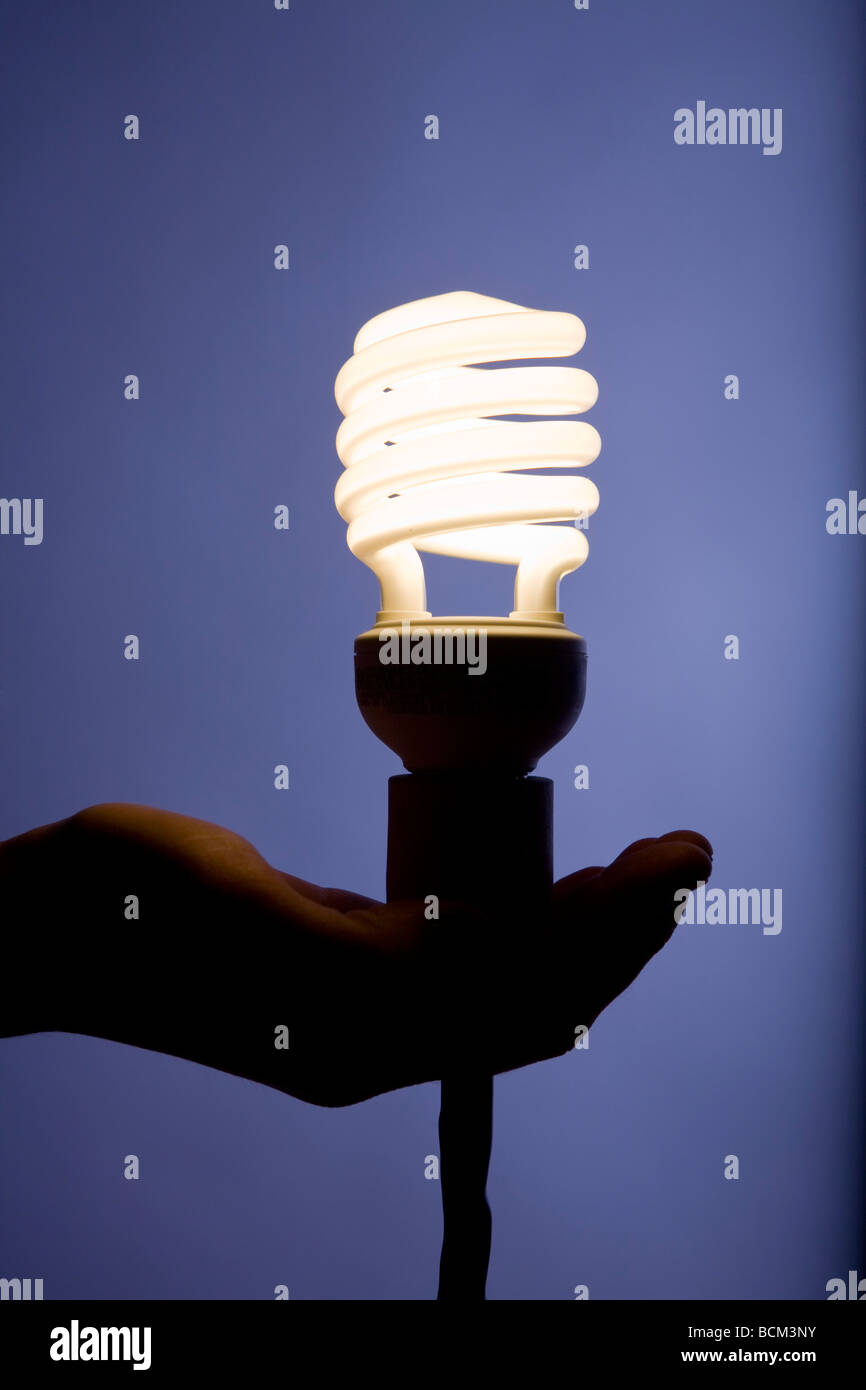 Mano che tiene una nuova energia efficiente compatto per lampade fluorescenti Foto Stock
