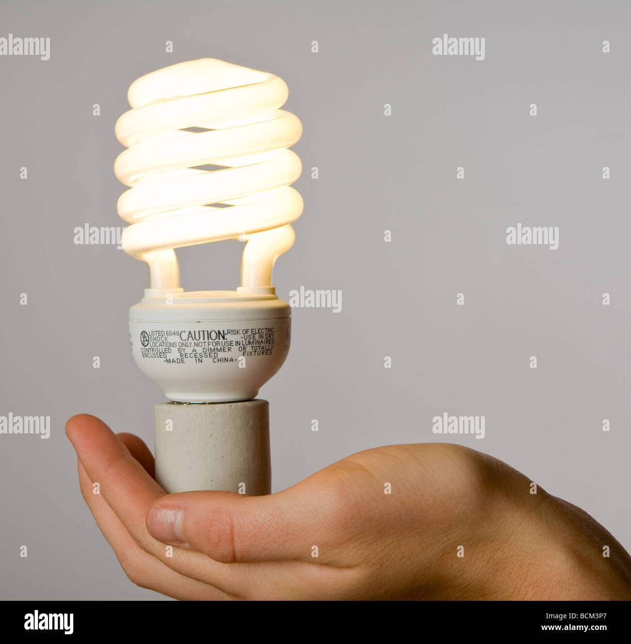 Mano che tiene una nuova energia efficiente compatto per lampade fluorescenti Foto Stock