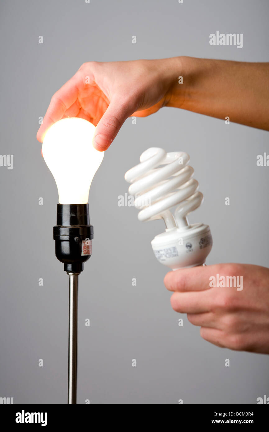 La sostituzione di una vecchia lampadina con una maggiore efficienza energetica compatta lampadina fluorescente Foto Stock
