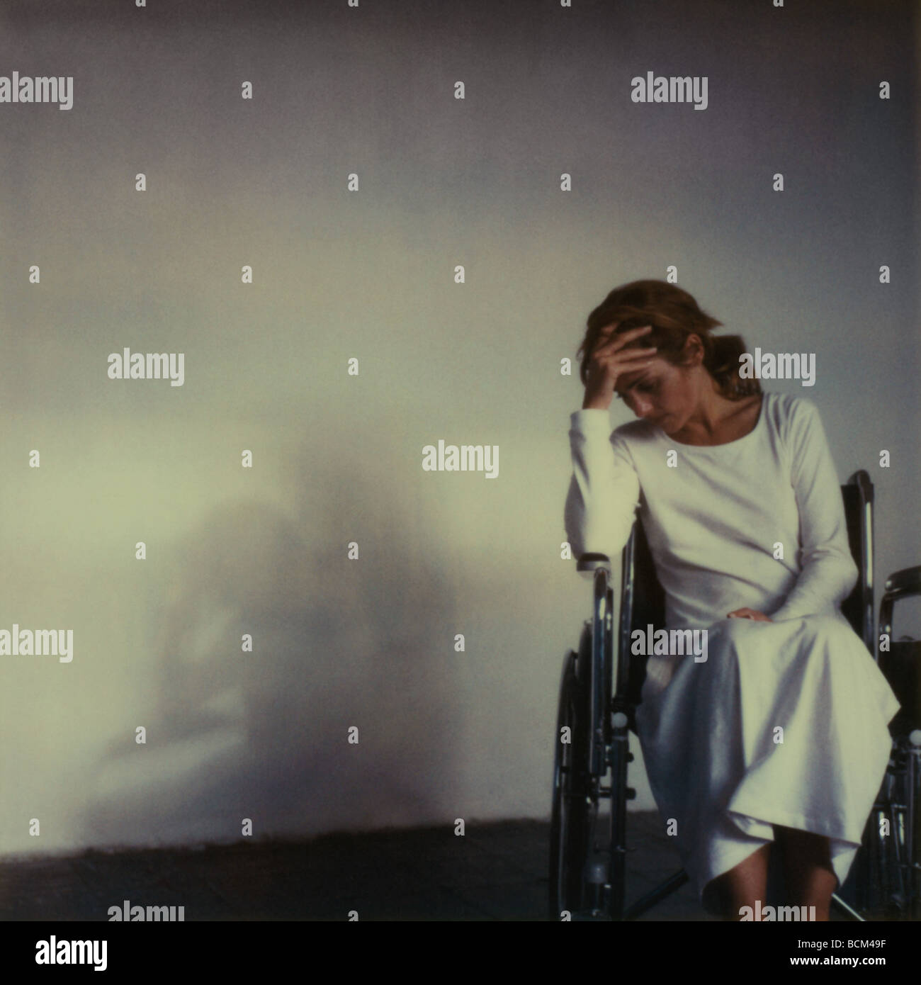 Donna seduta in sedia a rotelle testina di trattenimento Foto Stock