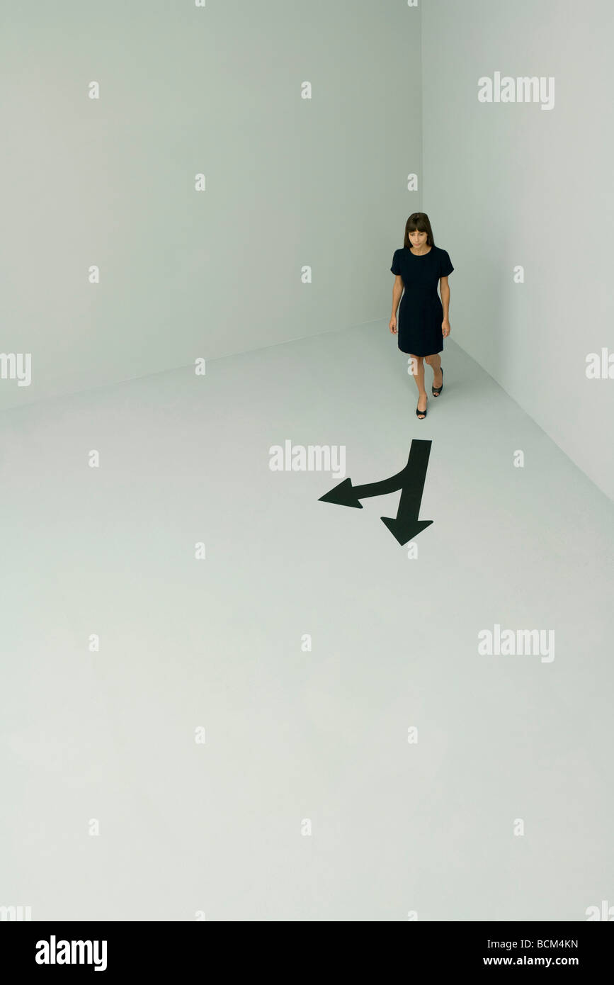 Donna che cammina, frecce verso direzioni diverse, ad alto angolo di visione Foto Stock