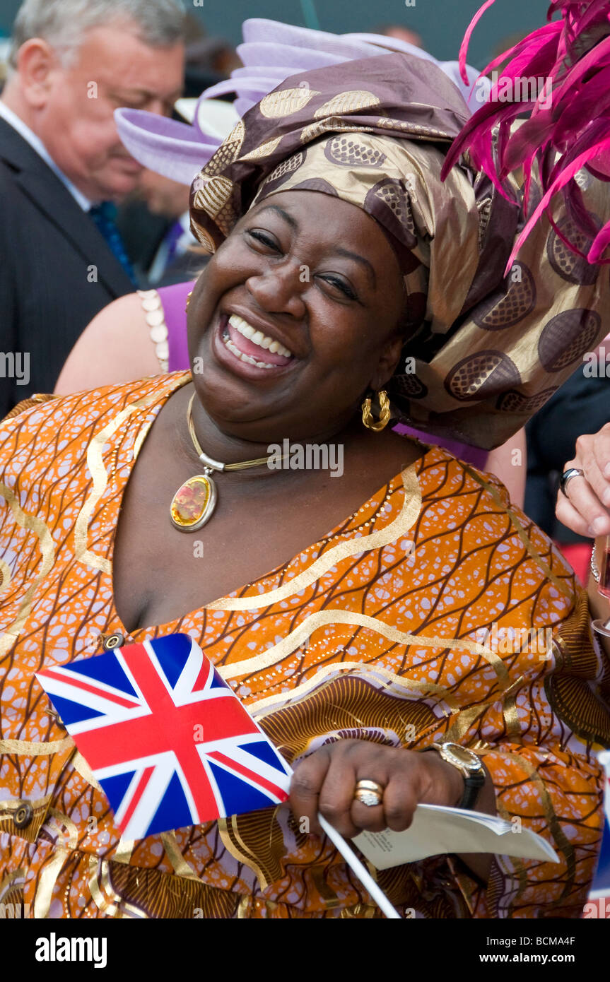 Una donna nera a ridere e tenendo una bandiera britannica Royal Ascot corse di cavalli, Signore giorno, Berkshire, Inghilterra, Regno Unito Foto Stock