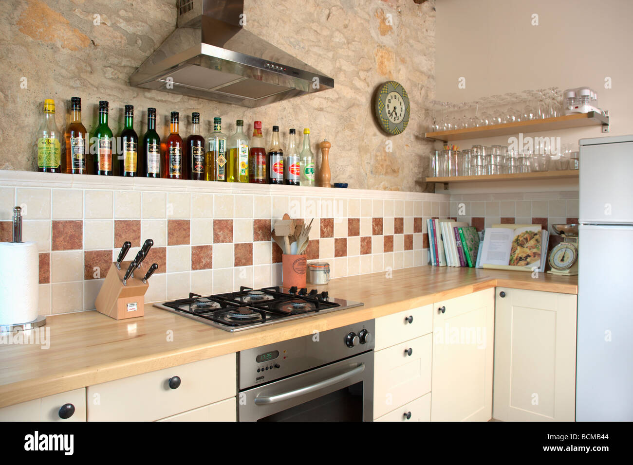 Cappa al di sopra del piano di cottura e forno in beige piccola cucina con  piano di lavoro in legno e piastrelle di seguito esposta parete in pietra  Foto stock - Alamy