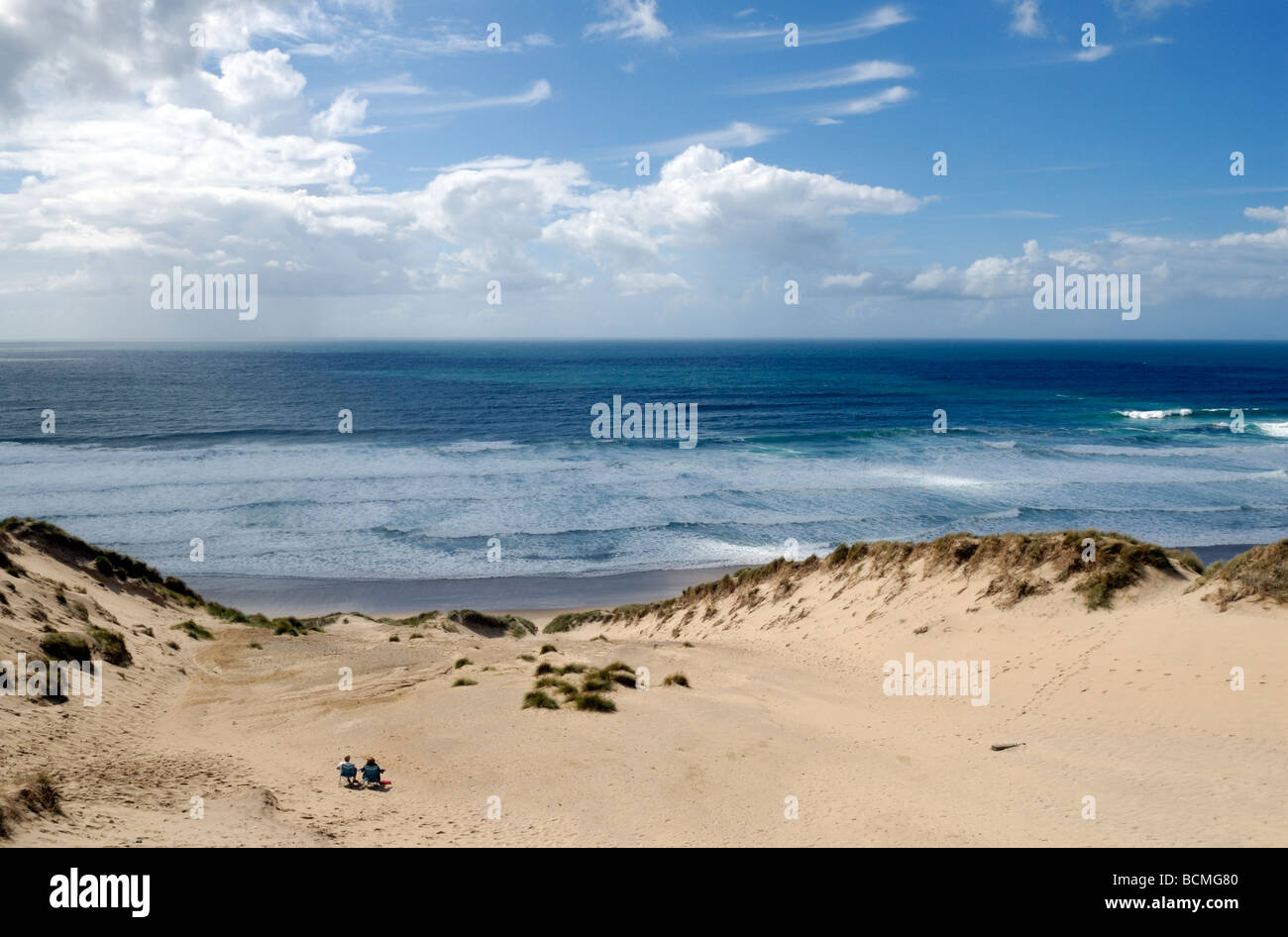 Un giovane seduto in dune di sabbia a guardare la vista Foto Stock