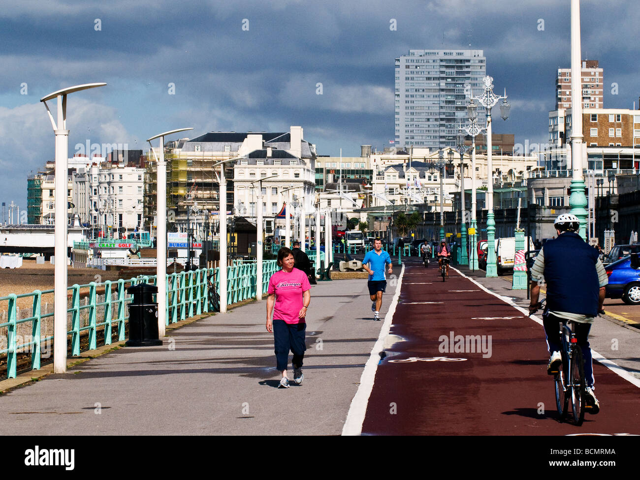 Persone in esecuzione a piedi e in bicicletta di fronte al mare a Brighton in Sussex. Foto Stock