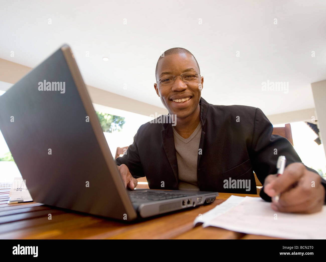 Giovane imprenditore cerca dal computer portatile mentre lavora a casa Foto Stock