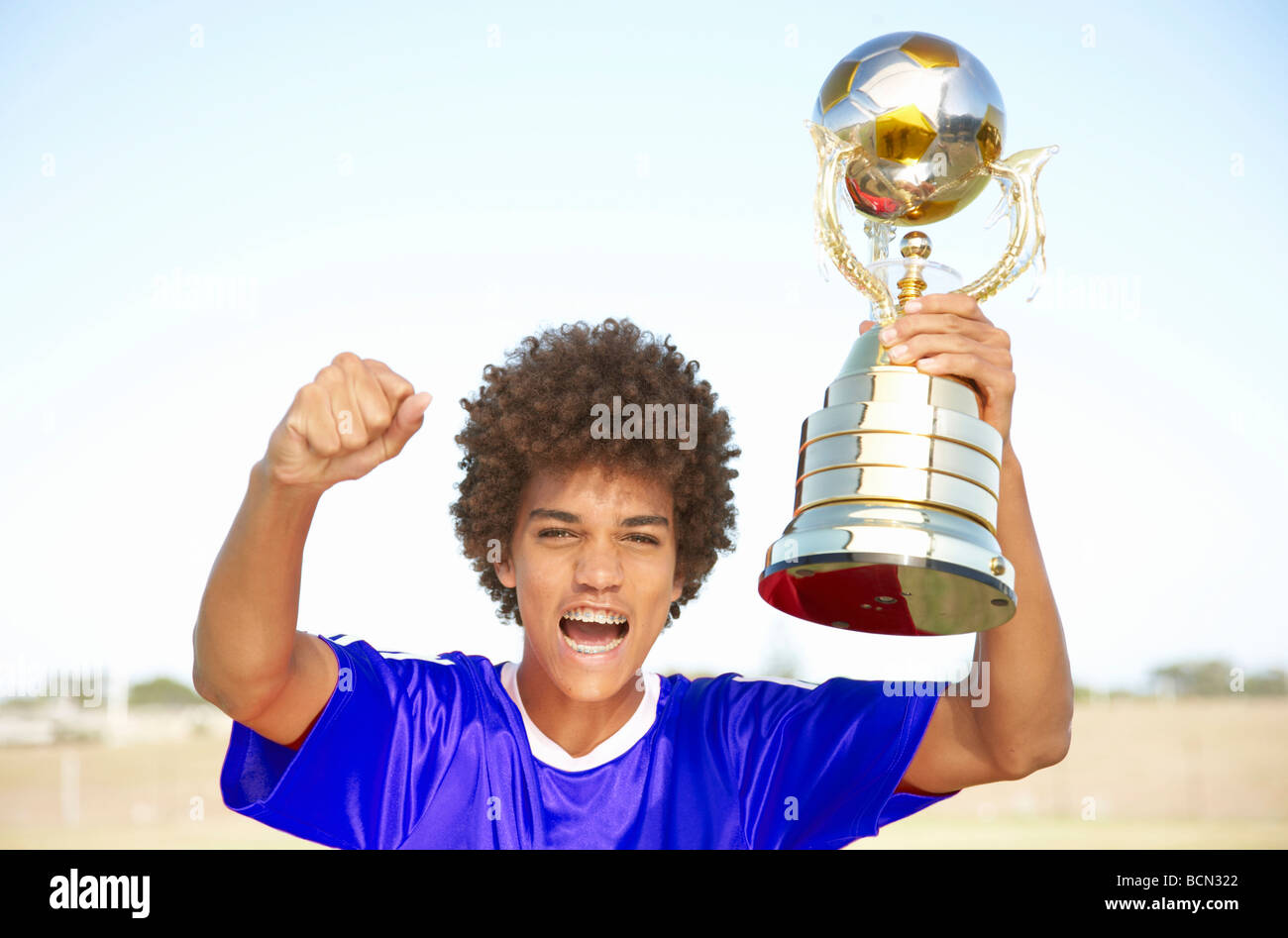 Giocatore di calcio holding vincitore trofeo con orgoglio Foto Stock