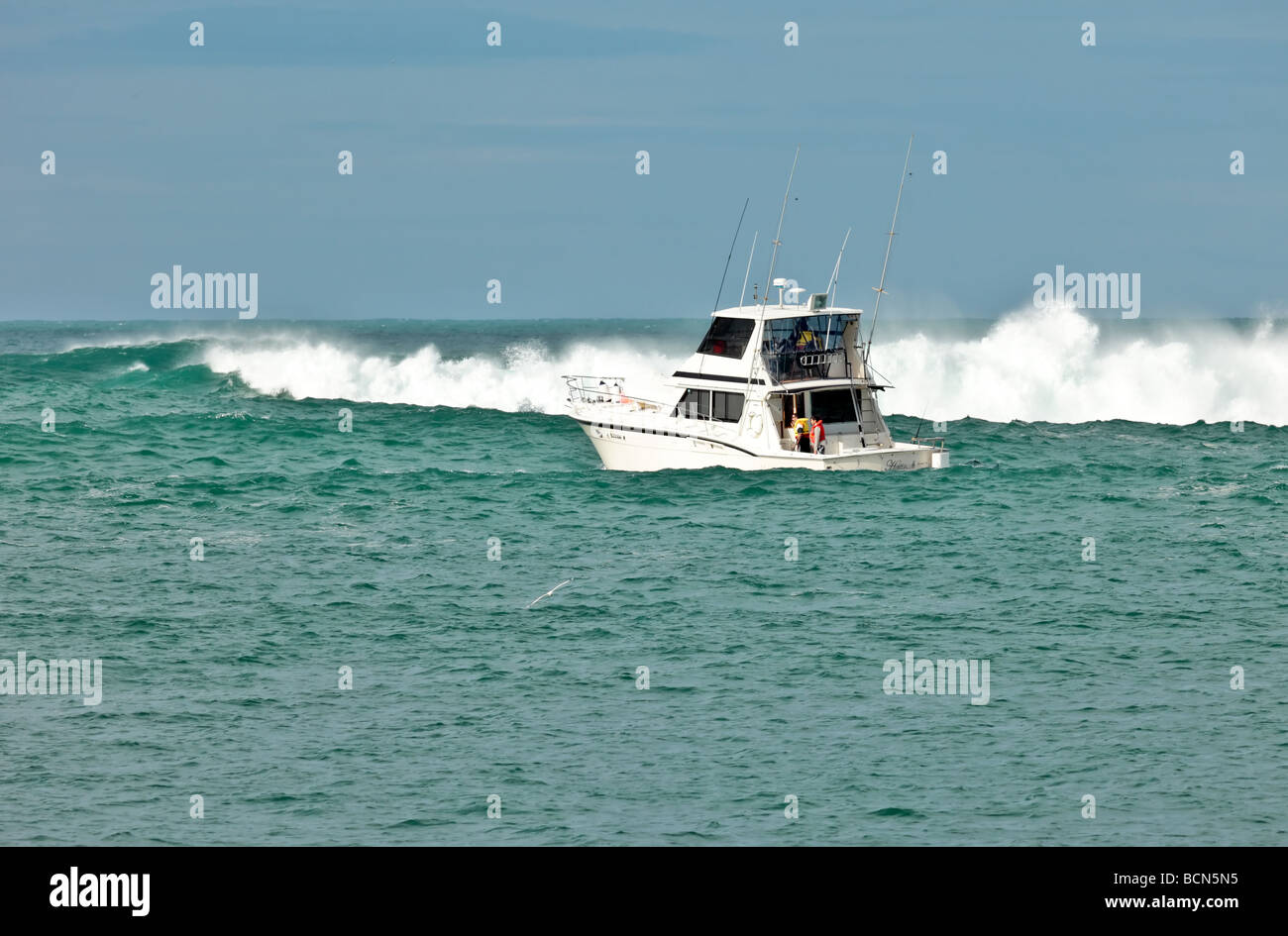 Barca da pesca si avvicina a mare mosso e si gonfia in entrata per l'oceano Foto Stock